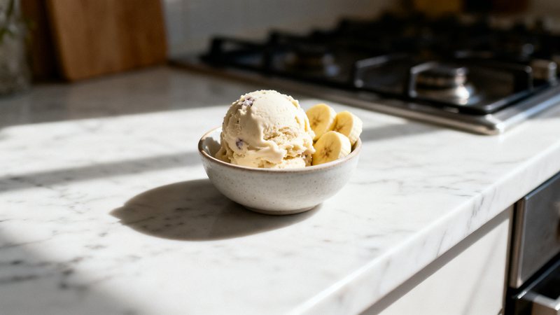 Skål med krämig proteinglass på banan och kvarg toppad med mörk choklad och bär